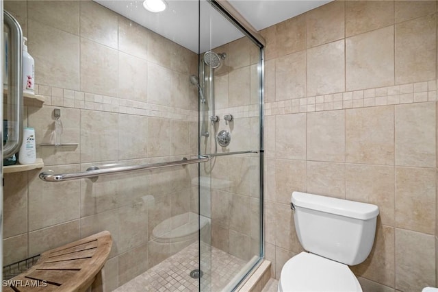 bathroom with a shower with door, tile walls, and toilet