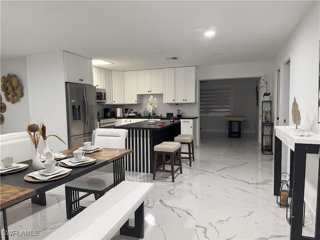 kitchen with backsplash, appliances with stainless steel finishes, and white cabinets