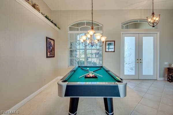 recreation room featuring french doors, billiards, tile patterned flooring, and a notable chandelier