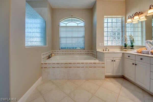 bathroom featuring vanity, tiled tub, and tile patterned floors