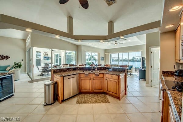 kitchen with sink, ceiling fan, stove, dark stone countertops, and stainless steel dishwasher