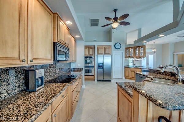 kitchen with tasteful backsplash, sink, dark stone counters, ceiling fan, and stainless steel appliances