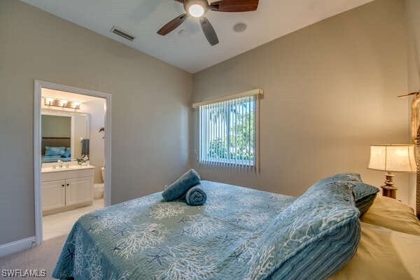 bedroom with lofted ceiling, ensuite bath, light colored carpet, and ceiling fan