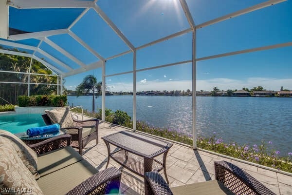 view of patio featuring a water view and glass enclosure