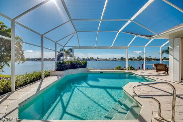 view of pool with a patio, a water view, and glass enclosure