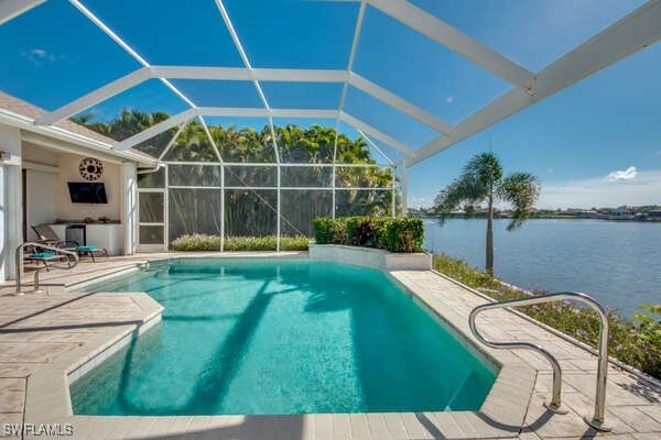 view of swimming pool featuring a water view, a patio area, and glass enclosure