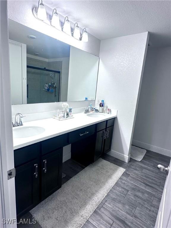 bathroom featuring an enclosed shower, vanity, hardwood / wood-style flooring, and a textured ceiling