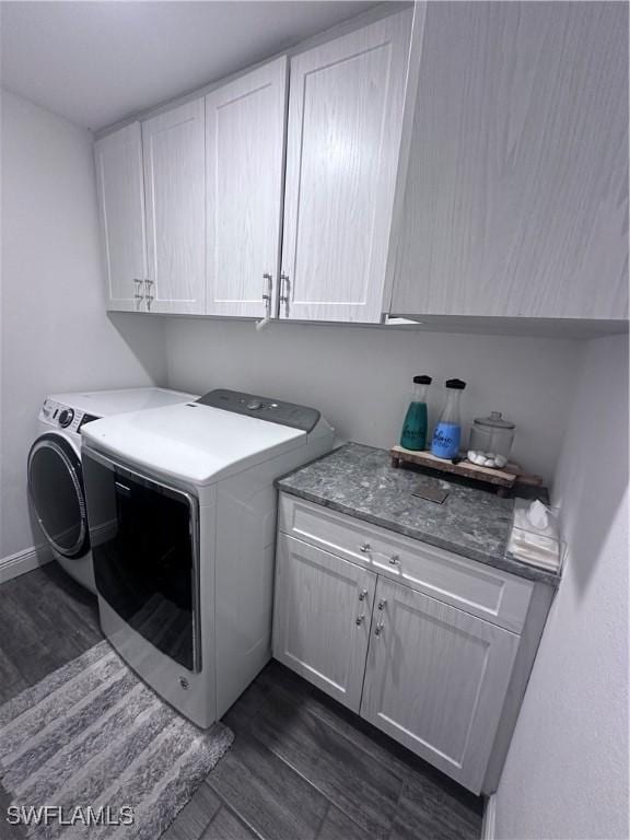 laundry room with dark hardwood / wood-style floors, cabinets, and washing machine and clothes dryer