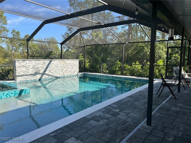 view of pool with a patio area and glass enclosure