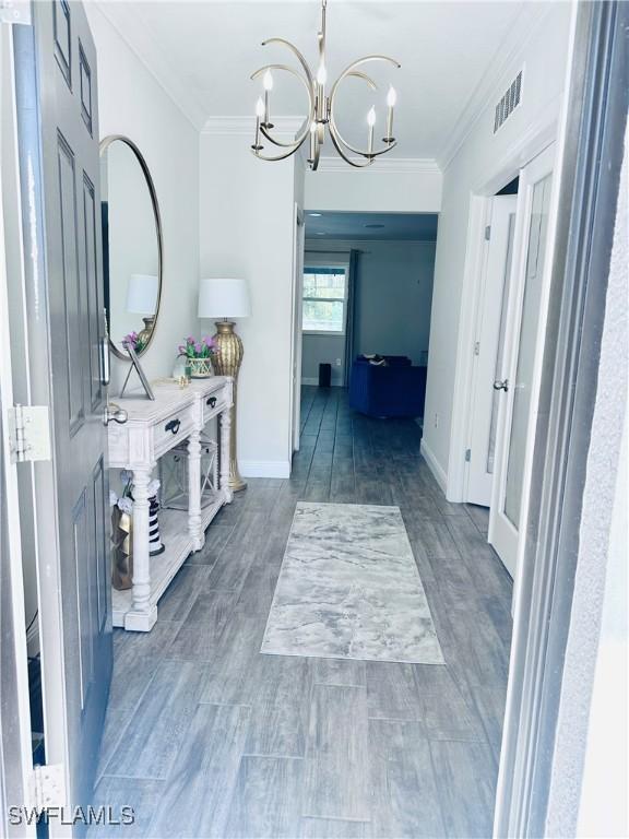 hallway with crown molding, a chandelier, and dark wood-type flooring