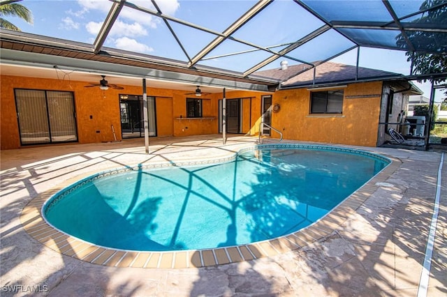 view of pool with a patio area, ceiling fan, and glass enclosure