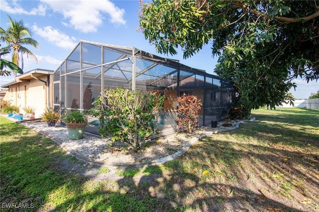 back of house with a lanai and a lawn