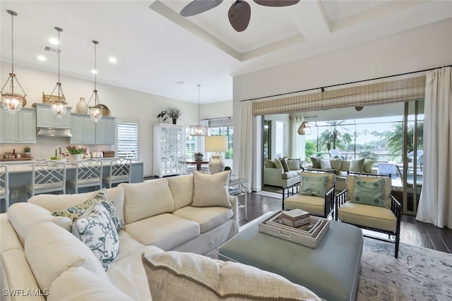 living room featuring dark hardwood / wood-style flooring, coffered ceiling, ceiling fan, crown molding, and beam ceiling