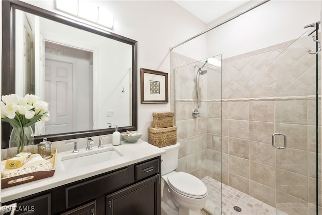 bathroom with vanity, a shower with door, and toilet