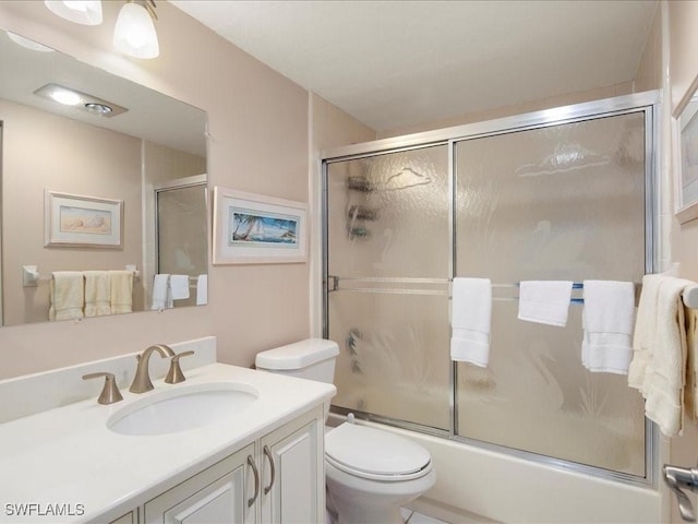 full bathroom with bath / shower combo with glass door, vanity, and toilet