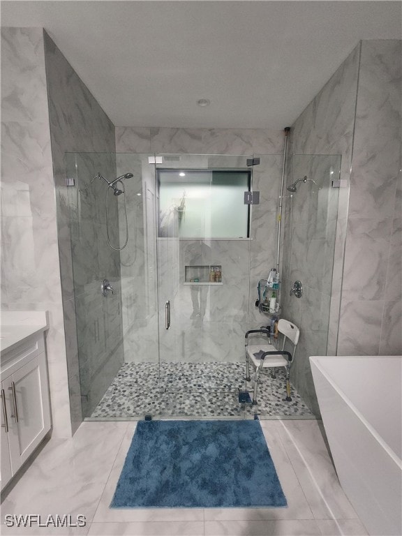 bathroom with independent shower and bath, vanity, and tile walls