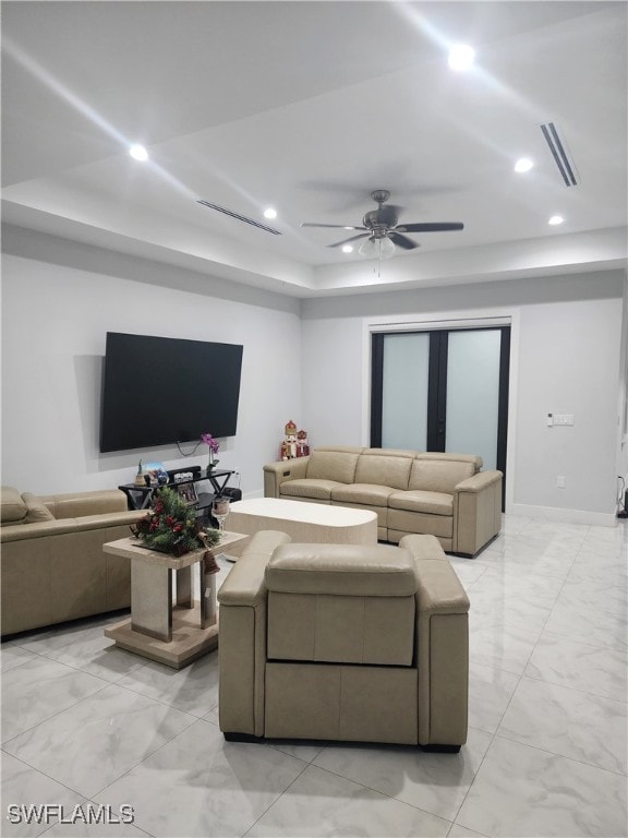 living room with ceiling fan and a tray ceiling