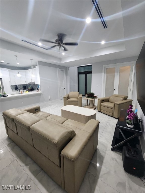 living room with ceiling fan and a tray ceiling