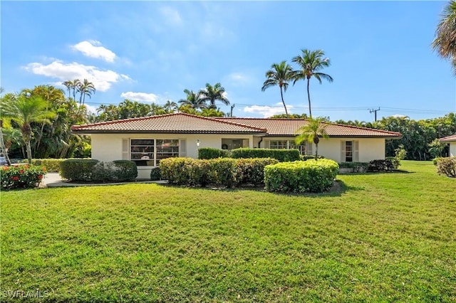 view of front of property with a front yard, a tile roof, and stucco siding