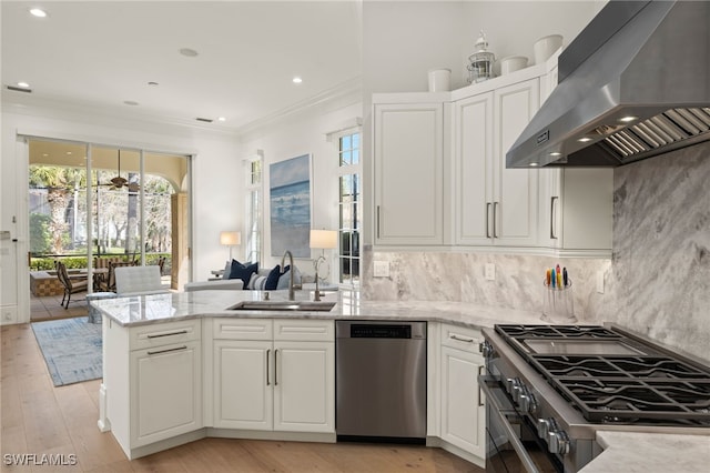 kitchen with appliances with stainless steel finishes, ventilation hood, white cabinetry, sink, and kitchen peninsula