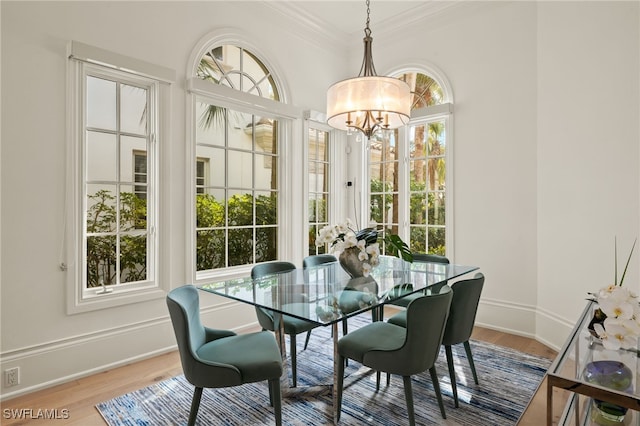 dining space with ornamental molding, plenty of natural light, hardwood / wood-style floors, and a chandelier