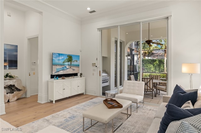 living room with ceiling fan, ornamental molding, and light wood-type flooring