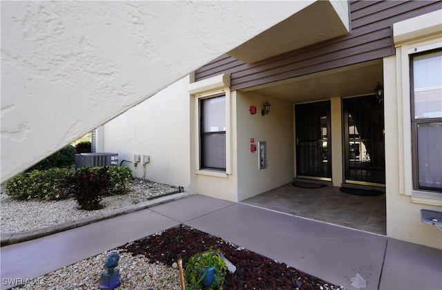 property entrance featuring central AC unit, a patio area, and stucco siding