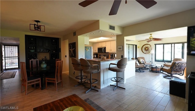 kitchen featuring visible vents, appliances with stainless steel finishes, a breakfast bar, wood finished floors, and a peninsula