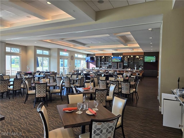 dining space featuring a raised ceiling and beamed ceiling