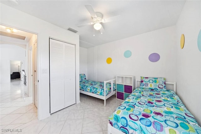 tiled bedroom with ceiling fan and a closet