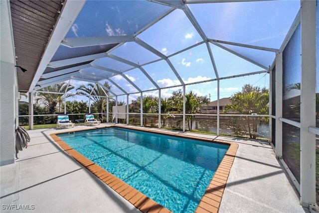 view of pool with a patio, a water view, and glass enclosure