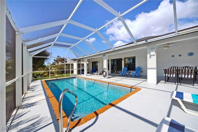 view of pool with a patio, ceiling fan, and glass enclosure