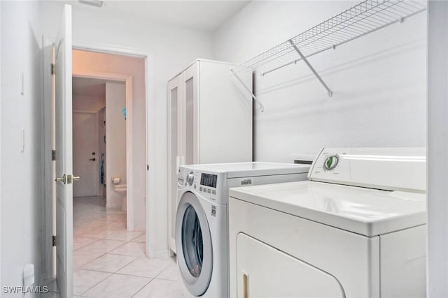 laundry room featuring washer and clothes dryer and light tile patterned floors