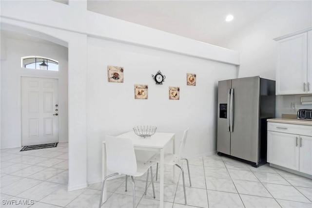 kitchen with white cabinetry, light tile patterned flooring, and stainless steel fridge with ice dispenser