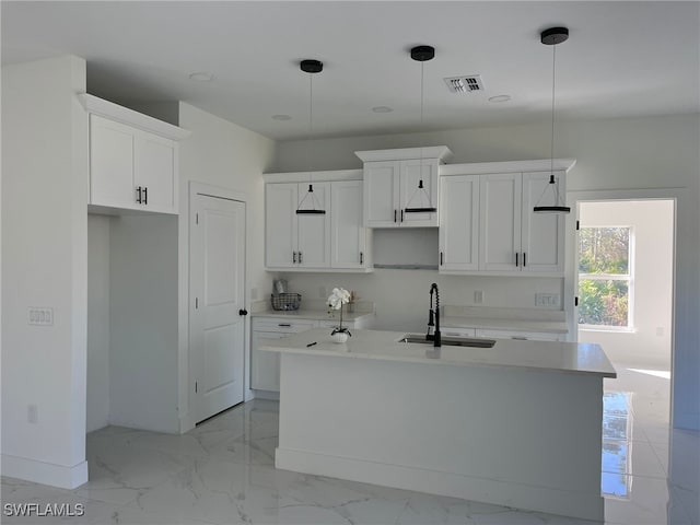 kitchen with pendant lighting, white cabinetry, an island with sink, and sink