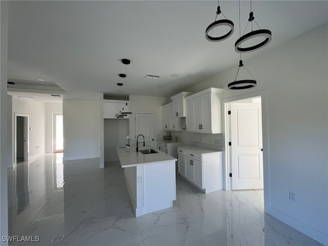 kitchen with pendant lighting, sink, an island with sink, and white cabinets