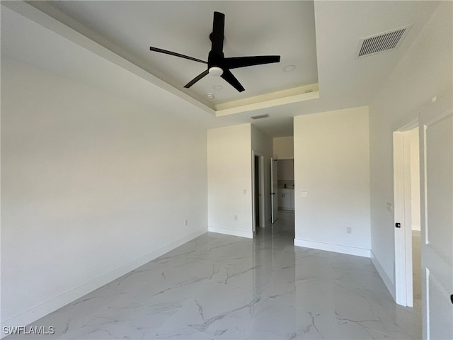 empty room featuring ceiling fan and a tray ceiling