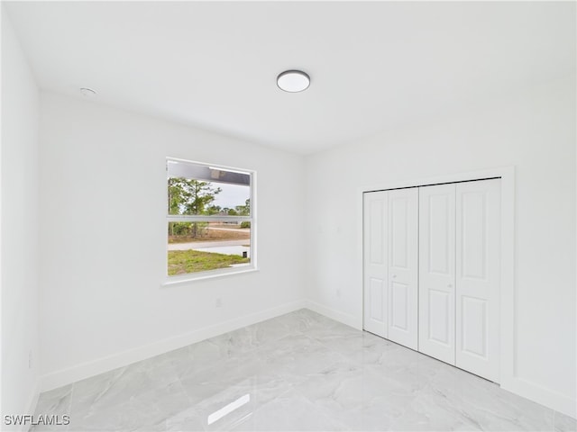 621 Allison St E, Lehigh Acres, FL 33974 - unfurnished bedroom featuring baseboards, marble finish floor, and a closet