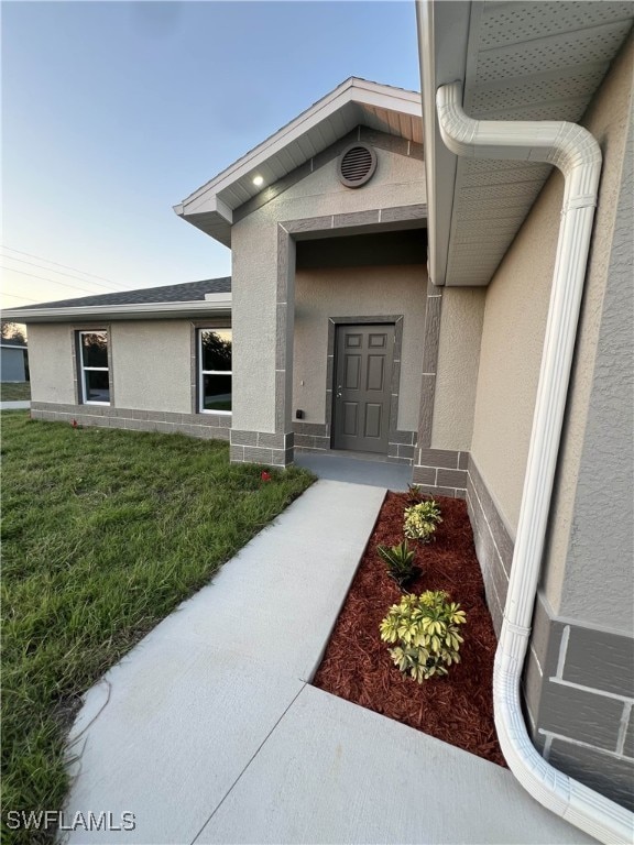 property entrance featuring a lawn