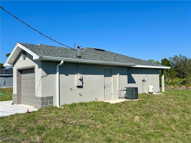 view of side of property featuring a garage, central air condition unit, and a lawn