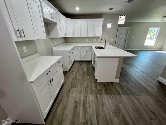 kitchen with hanging light fixtures, sink, a center island with sink, and white cabinets