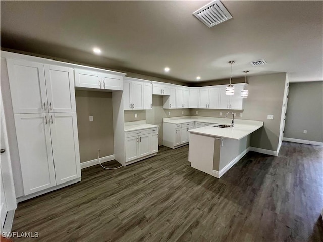 kitchen featuring hanging light fixtures, dark hardwood / wood-style floors, sink, and white cabinets