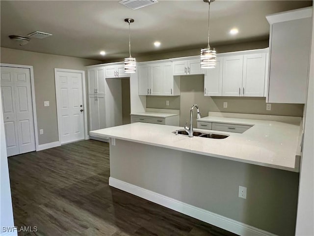 kitchen with white cabinetry, dark hardwood / wood-style floors, sink, and hanging light fixtures