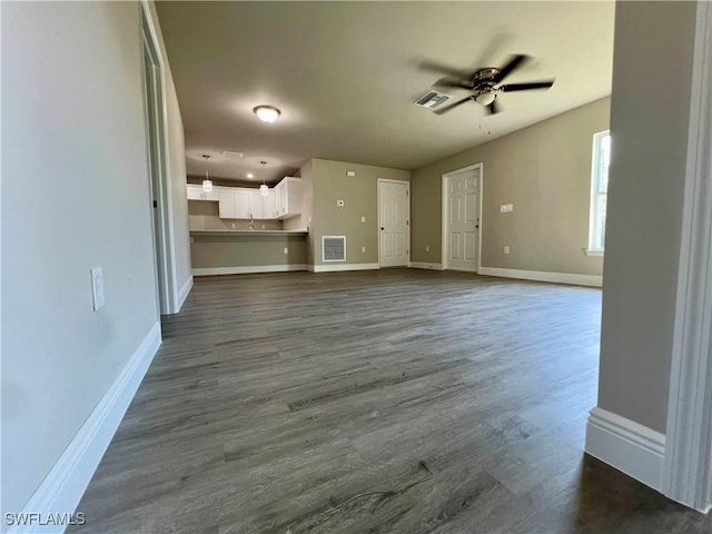 unfurnished living room featuring dark wood-type flooring, sink, and ceiling fan