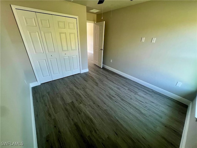 unfurnished bedroom with dark wood-type flooring, ceiling fan, and a closet