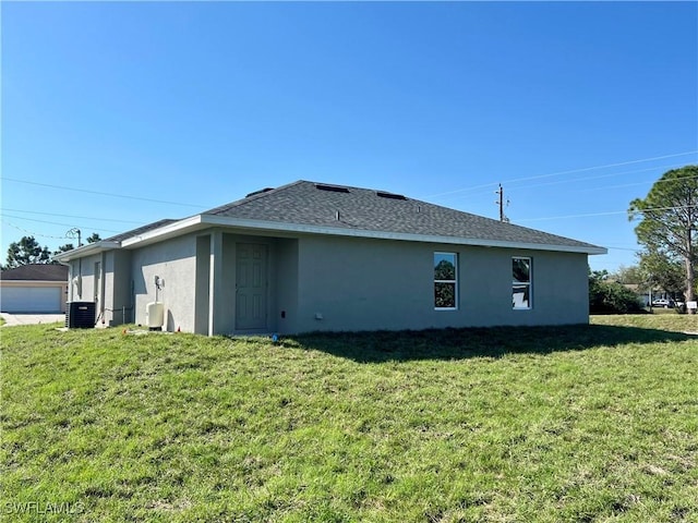 rear view of house with cooling unit and a yard