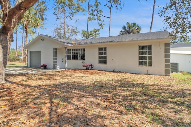 rear view of property featuring a garage and cooling unit