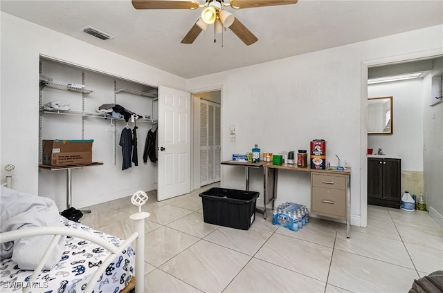 bedroom with light tile patterned floors, visible vents, baseboards, ceiling fan, and a closet