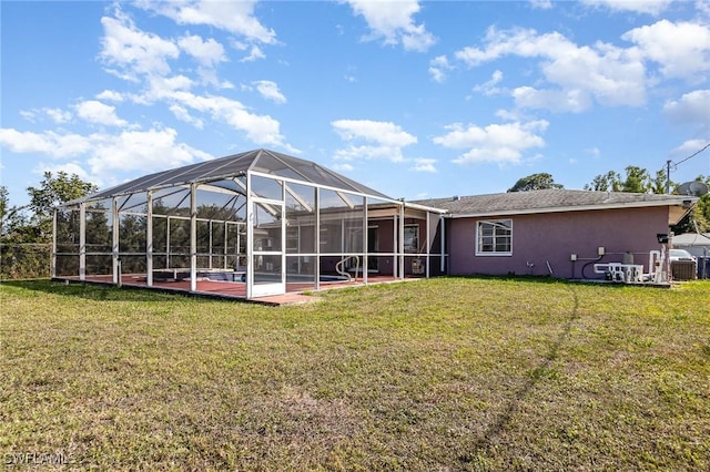 rear view of house featuring a lanai, a lawn, a patio, and stucco siding