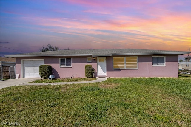 single story home featuring a garage, a yard, driveway, and stucco siding